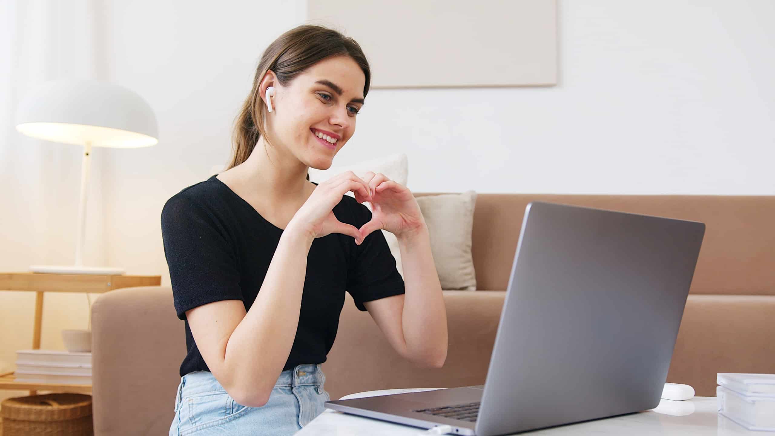 Woman making heart with hands on video call