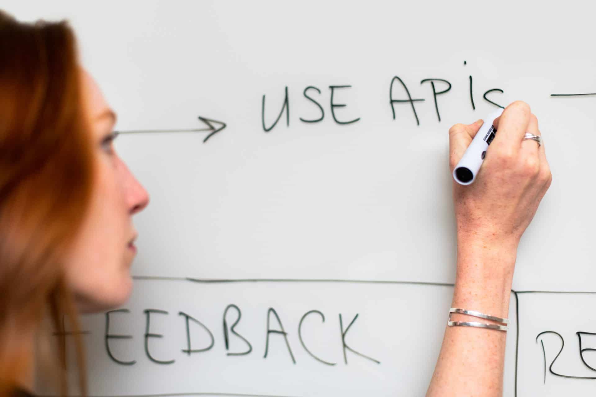 Woman writing API on whiteboard