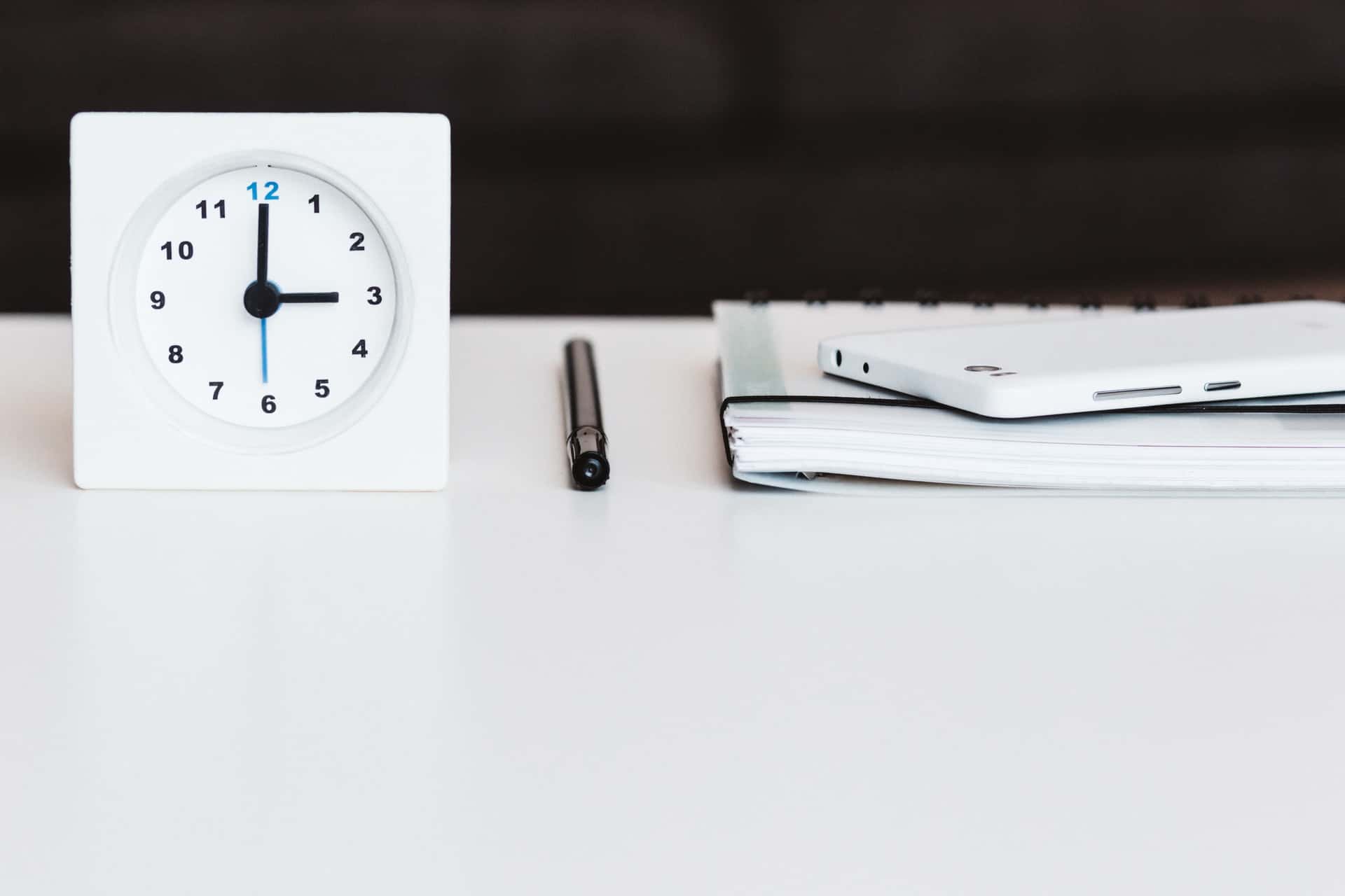 Clock and notebook on table