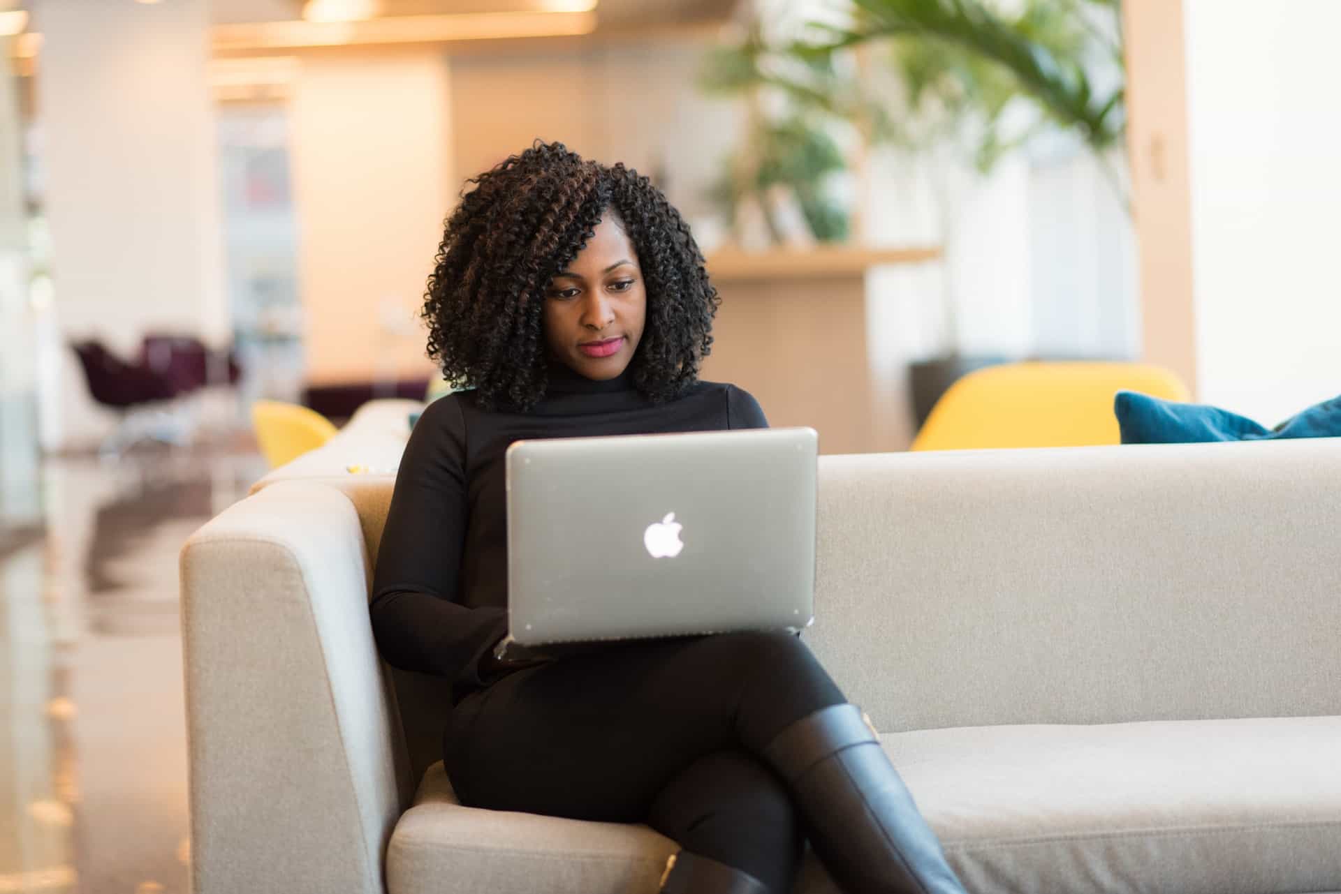 Woman sitting on sofa using laptop