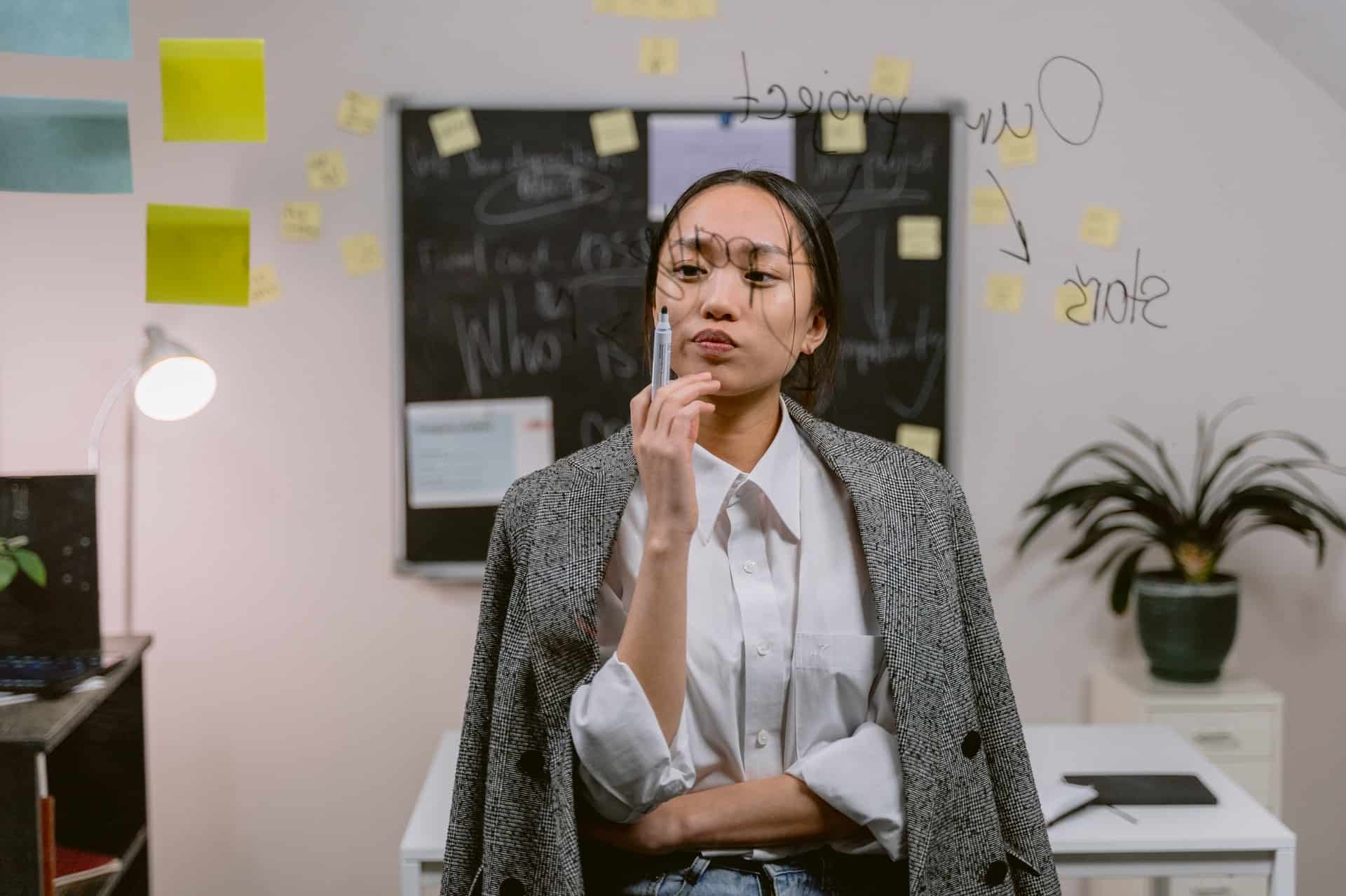 Woman thinking while holding marker