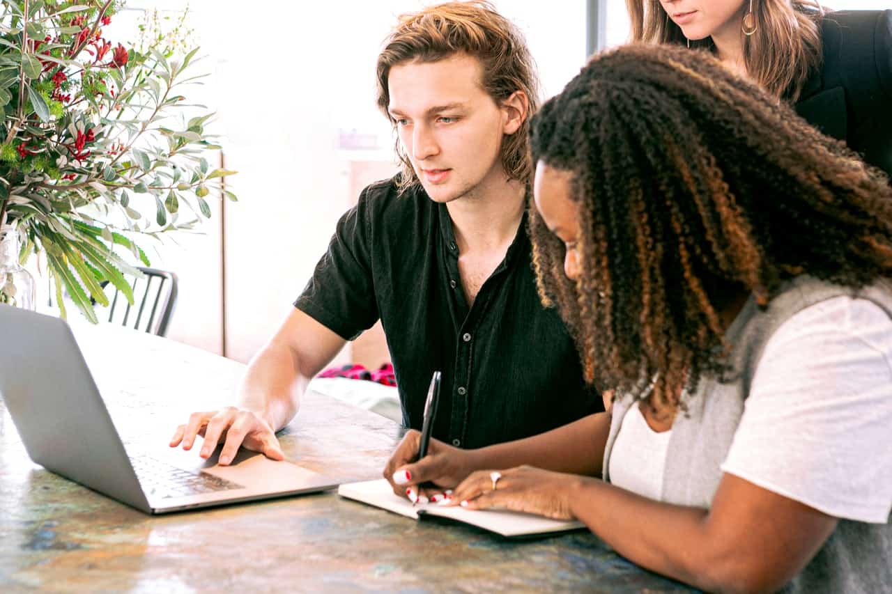 Man using laptop and woman taking notes