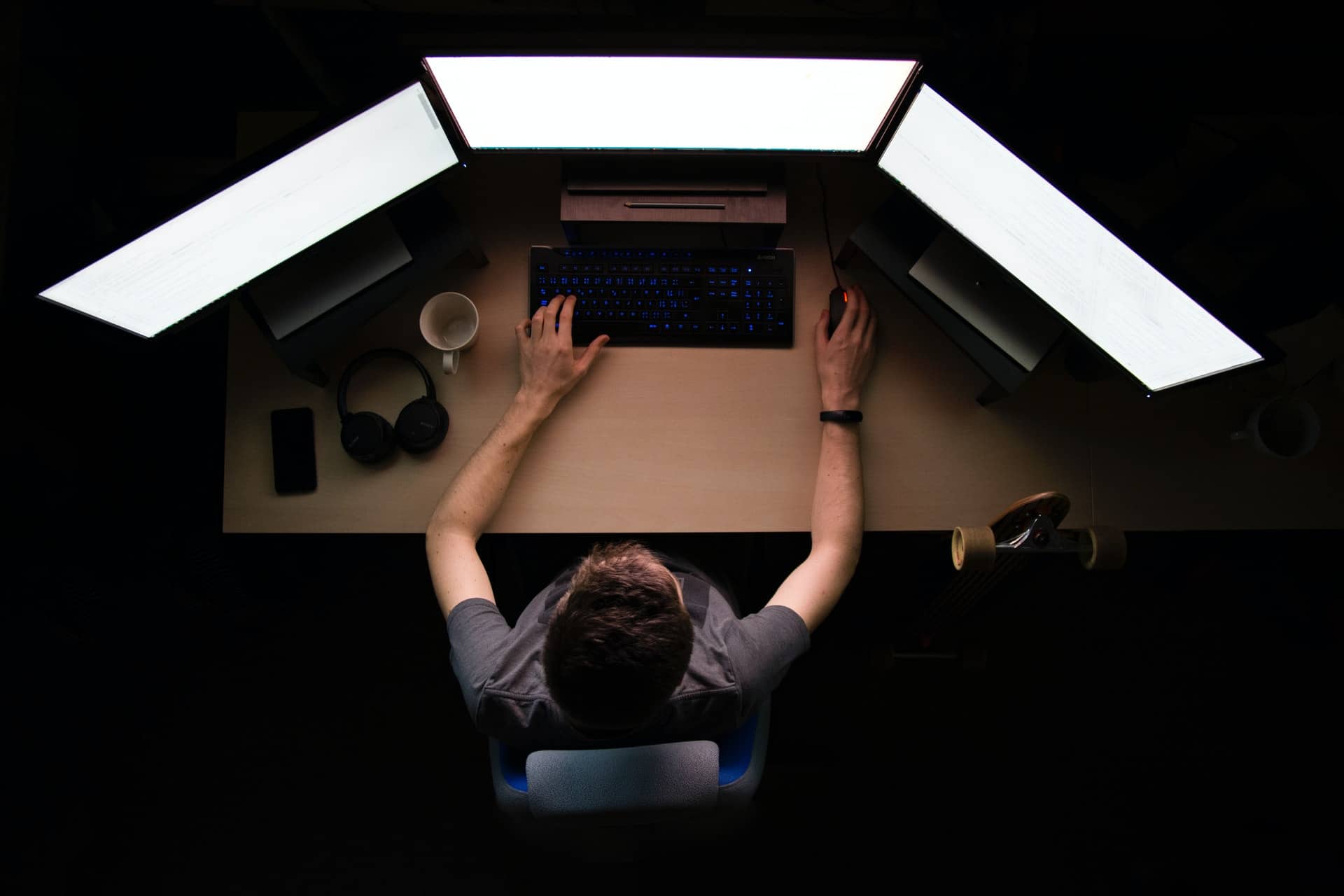 Man in front of three monitors