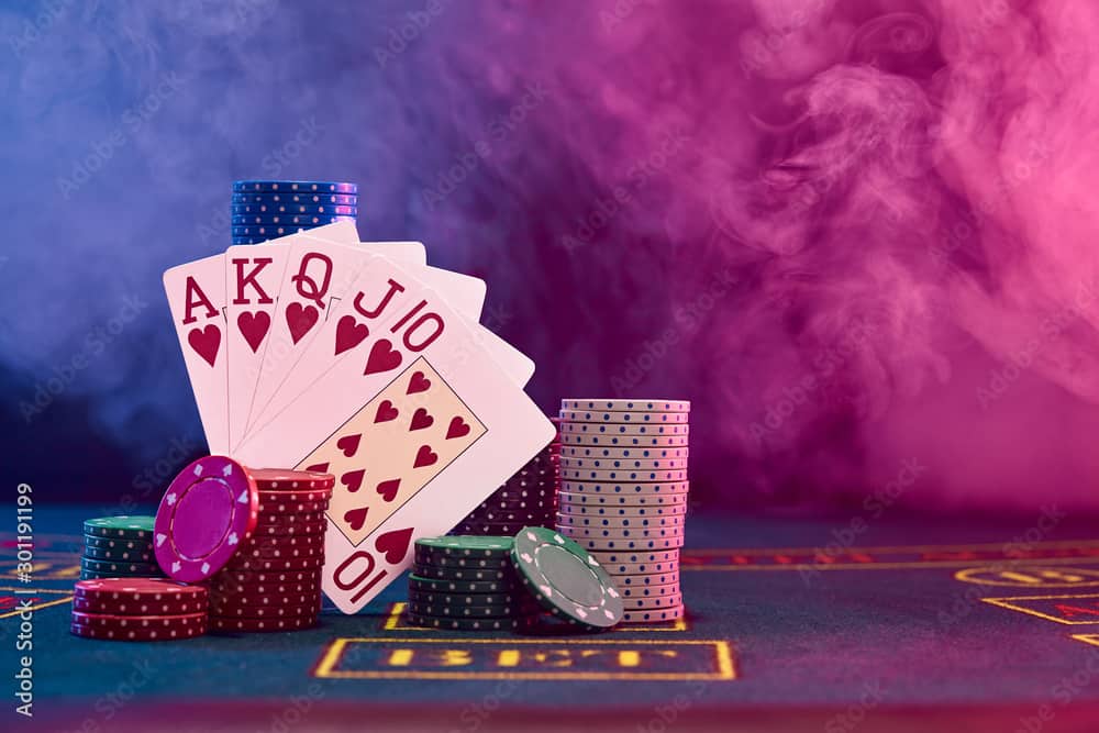 Winning combination in poker leaning on colored chips piles on blue cover of playing table. Black, smoke background, red and blue backlights. Casino.